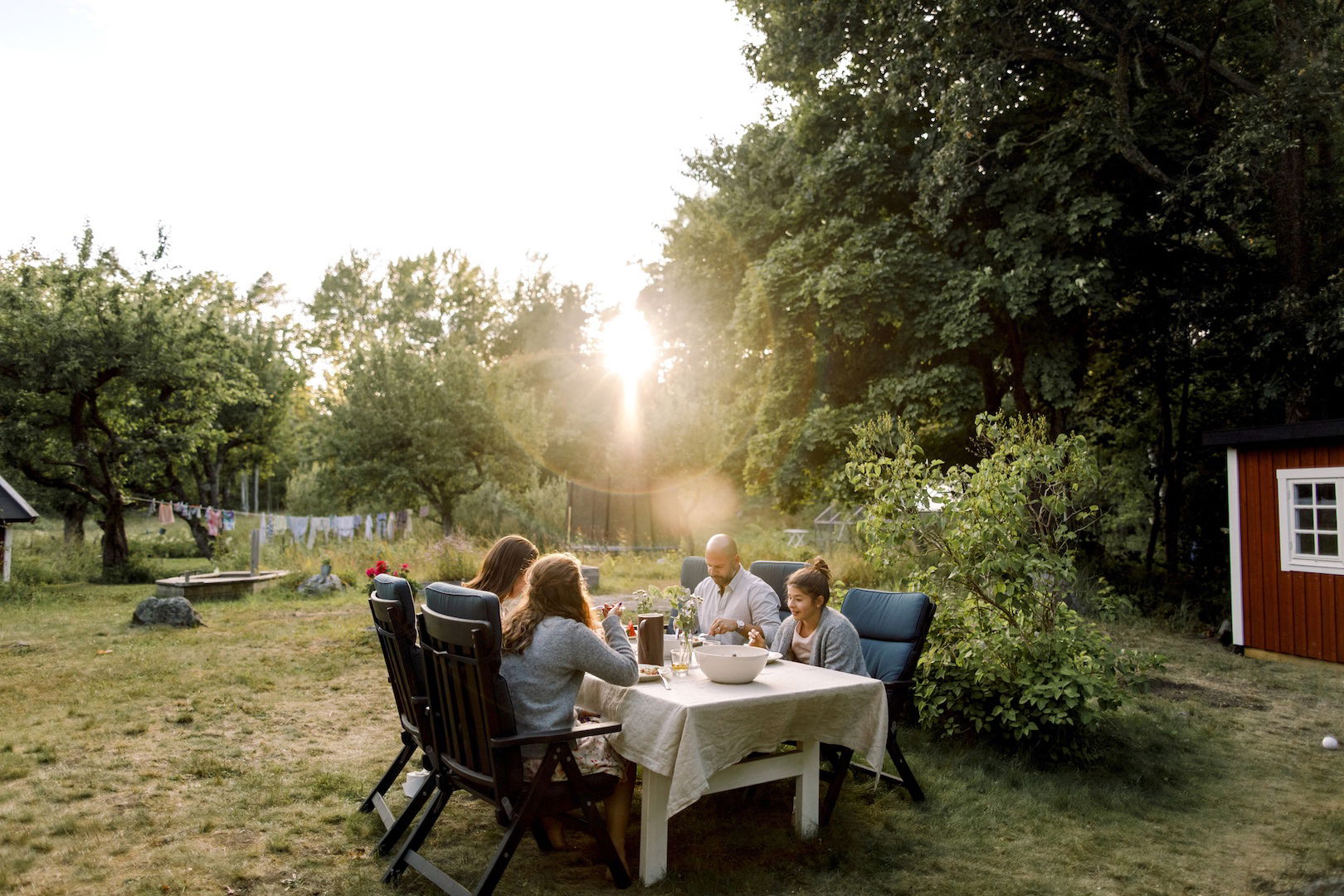 En familj äter middag i solnedgången i trädgården