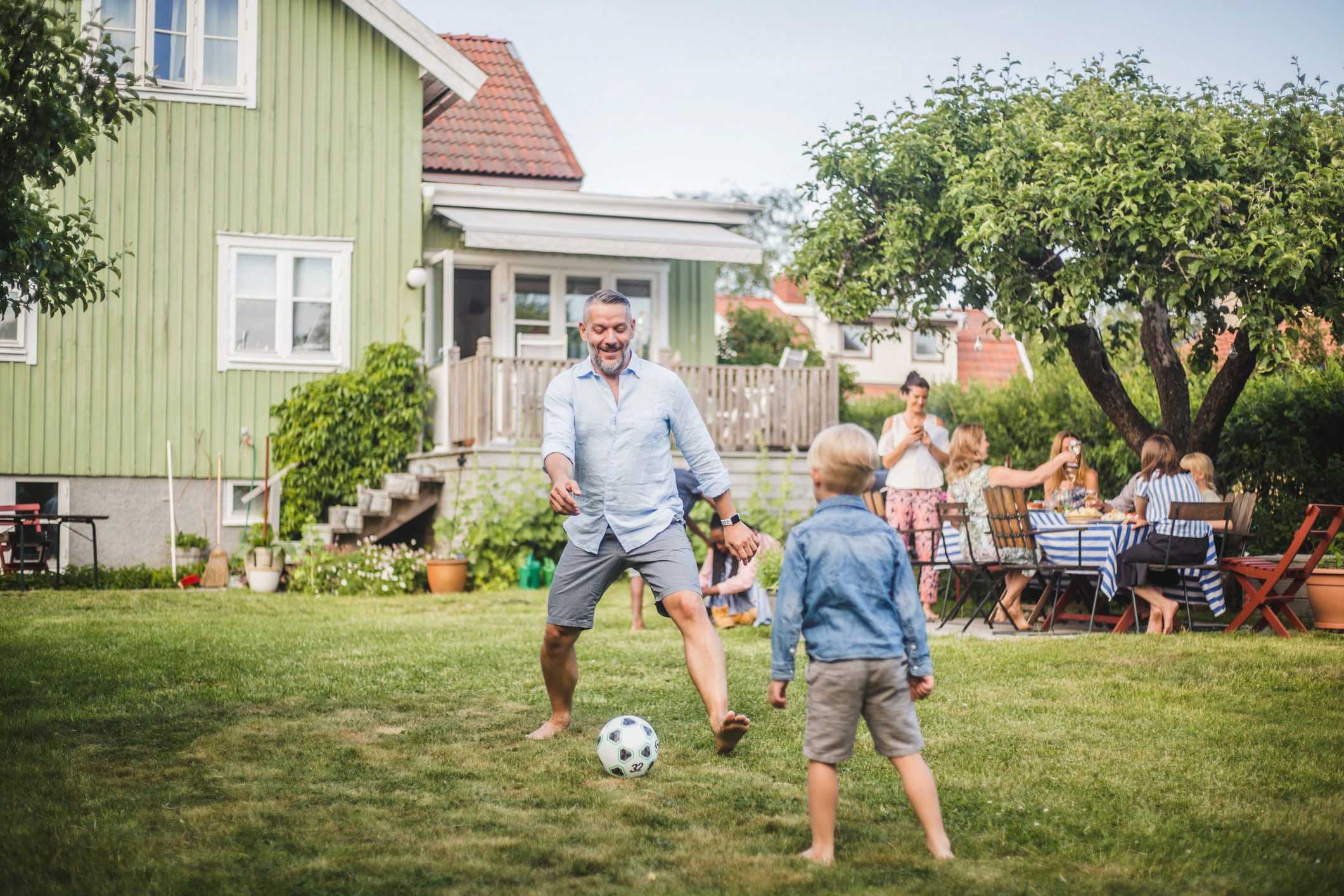 En pappa spelar fotboll med sin son i trädgården